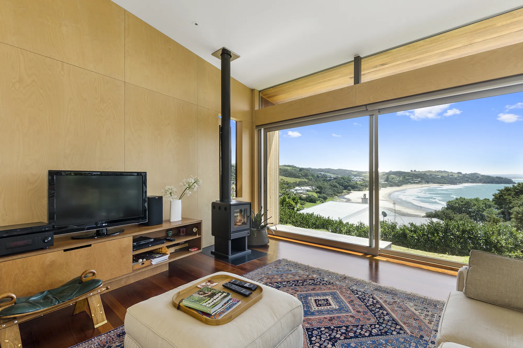Living space with a wood fire and full-height glazing to the sea