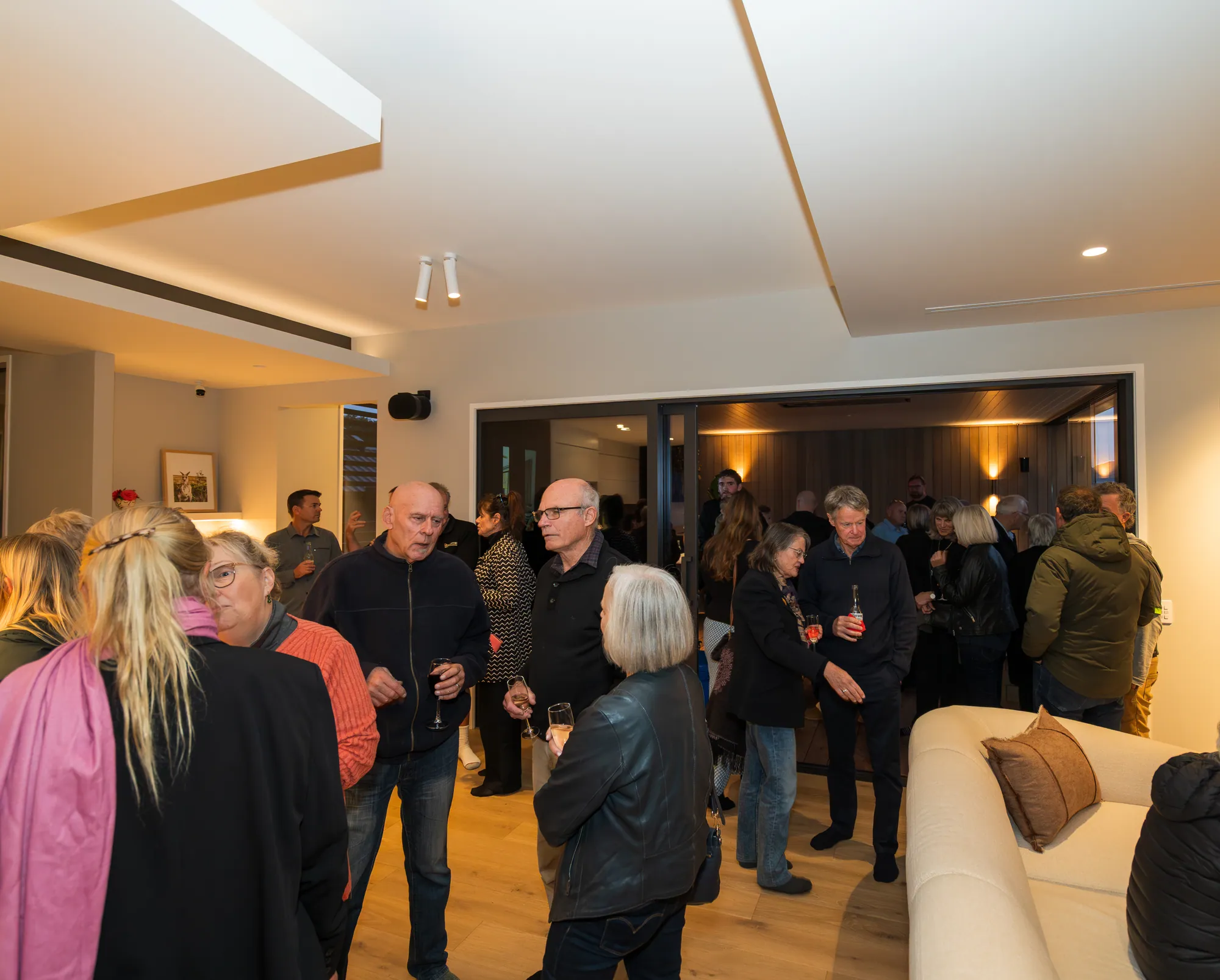 Guests at a Cogan client event, in a completed home with the doors open to the deck