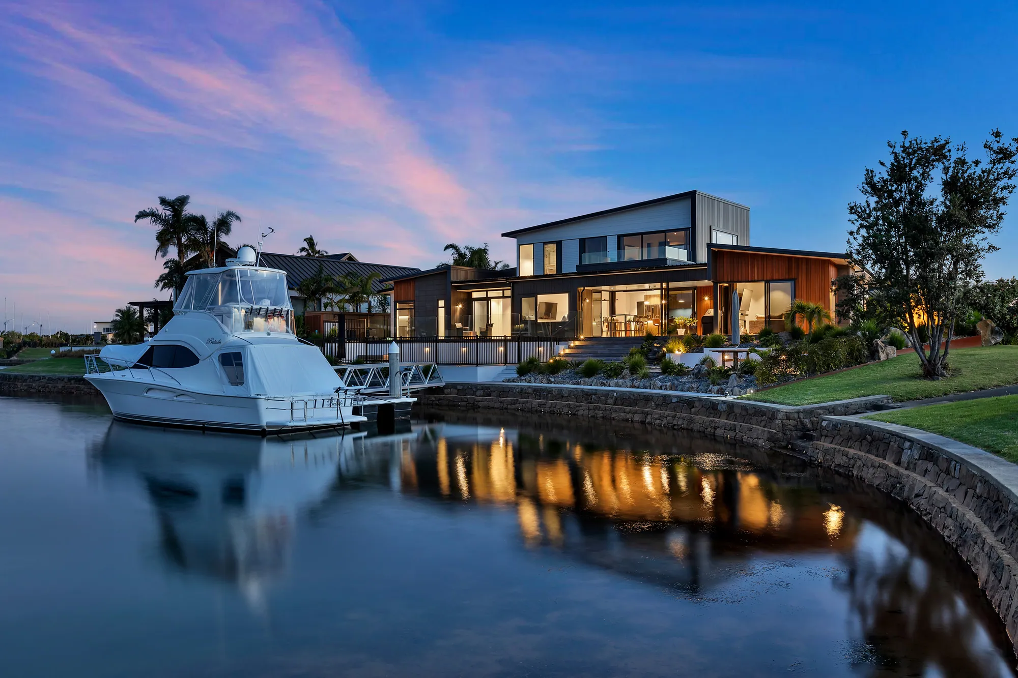 A Cogan-built canal home at dusk with a launch at the private jetty