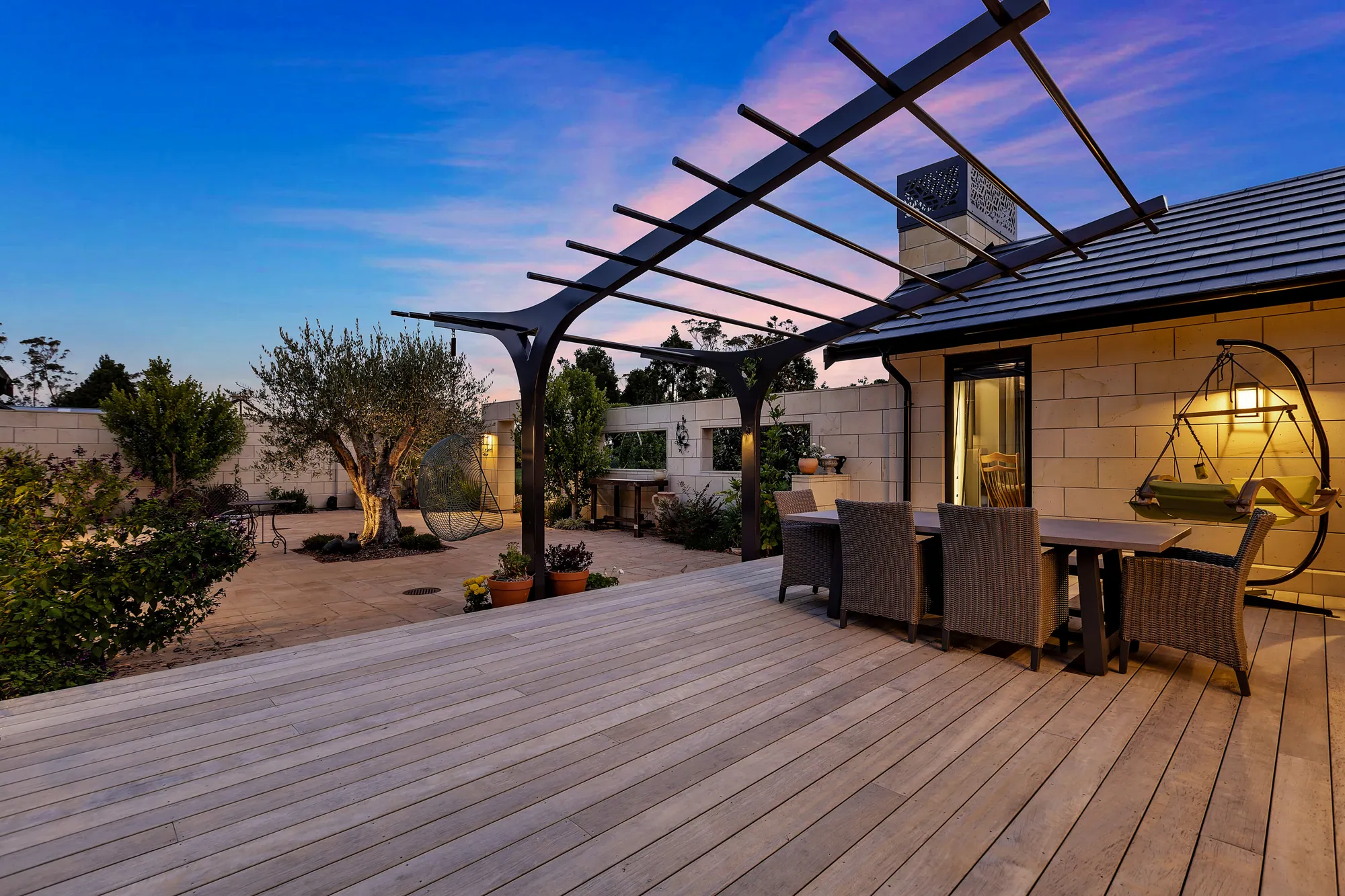 Timber deck and pergola beside a stone-clad home at dusk