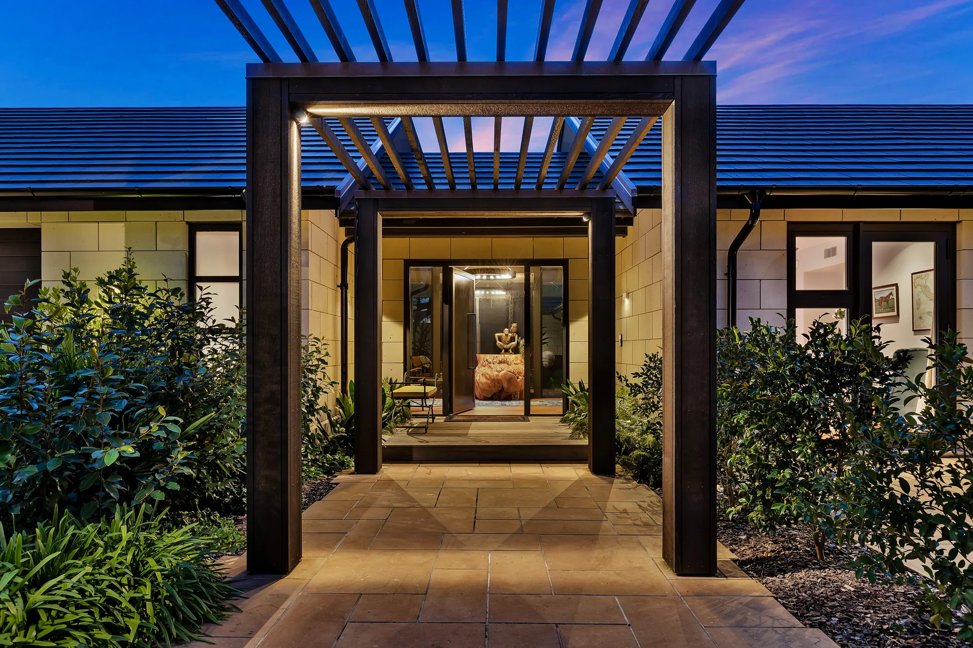 Lit entry pergola framing the front door at dusk