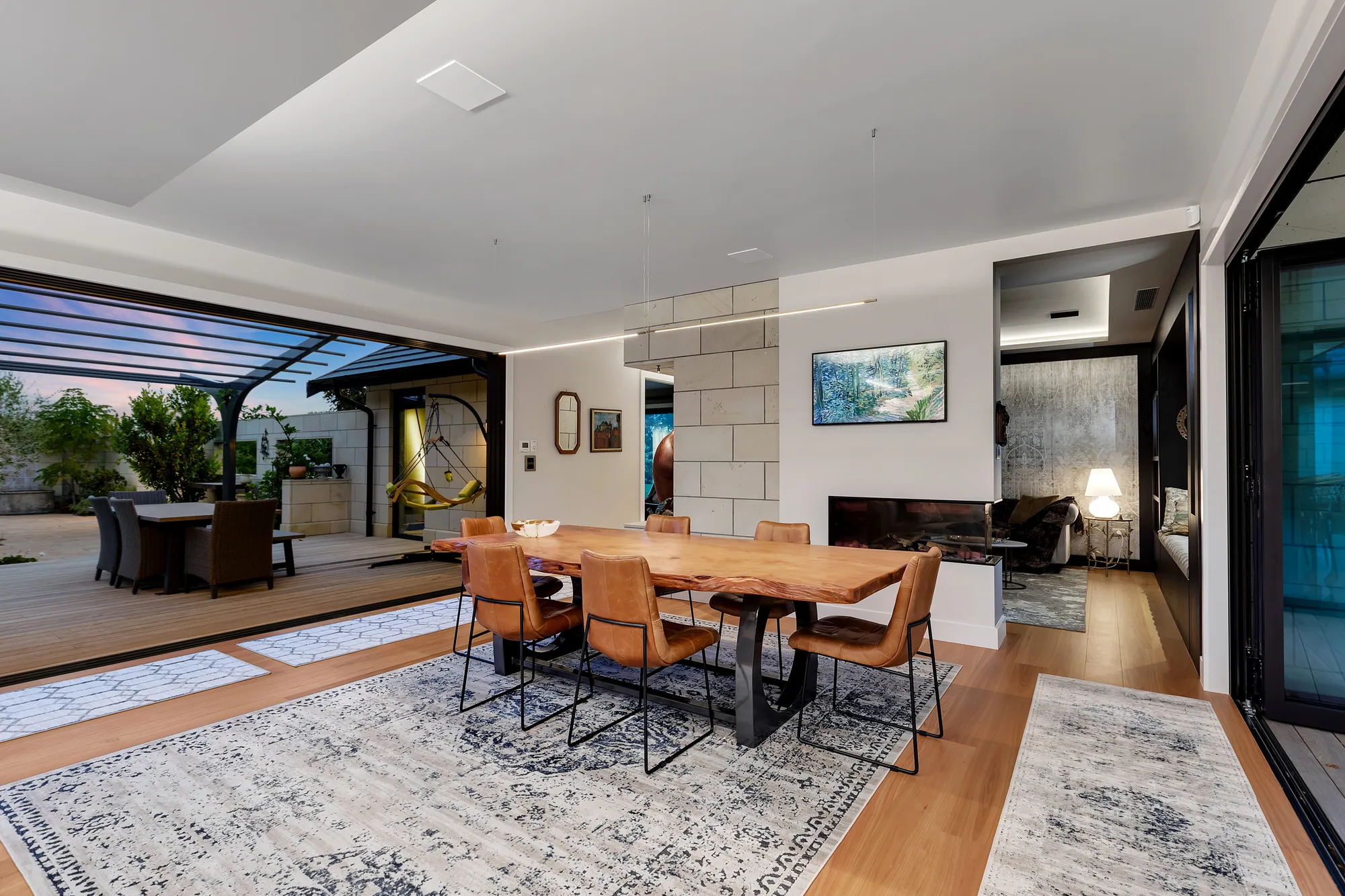 Dining room with a timber table, stone wall and fireplace