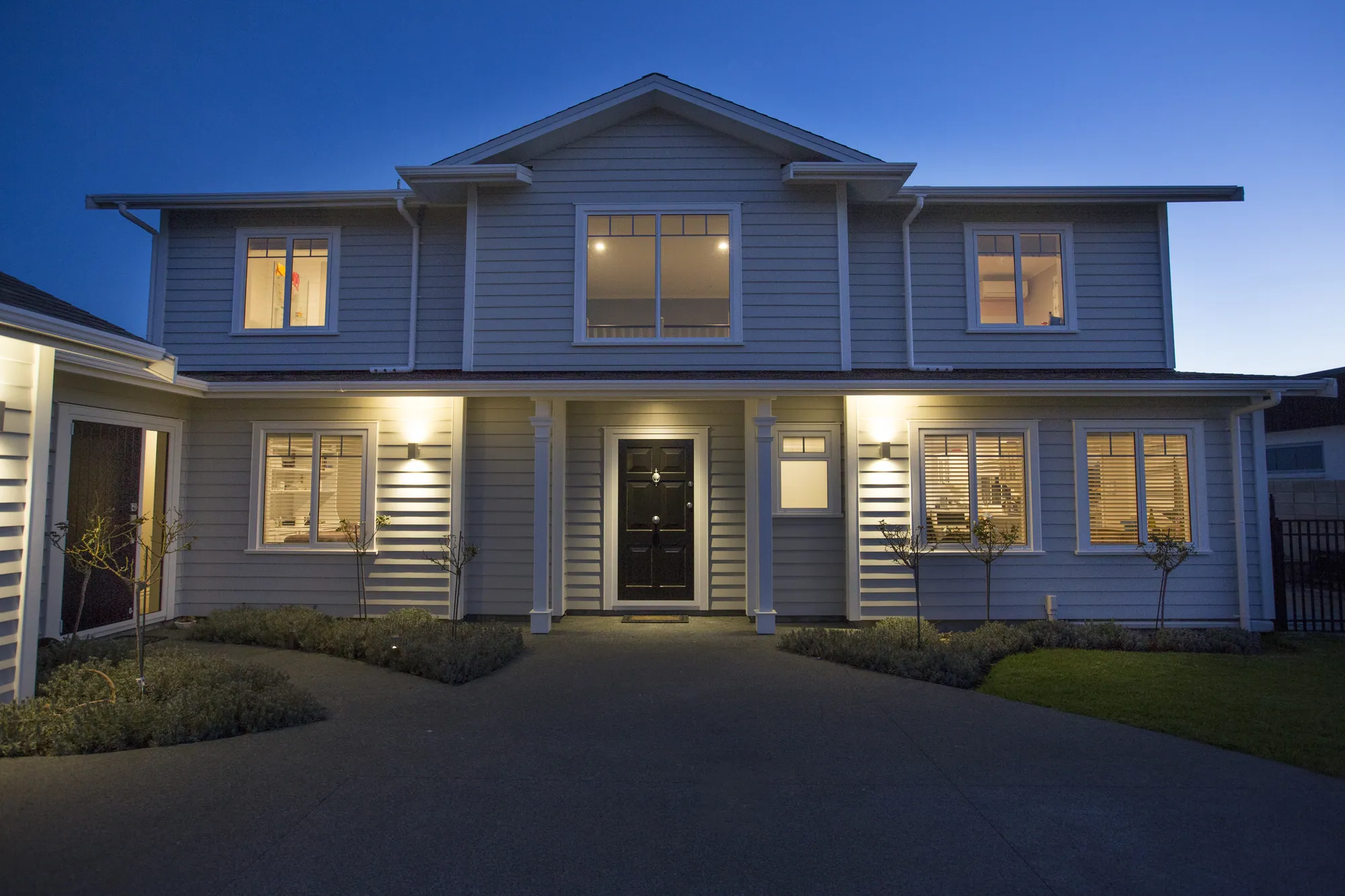Two-storey weatherboard home lit at dusk
