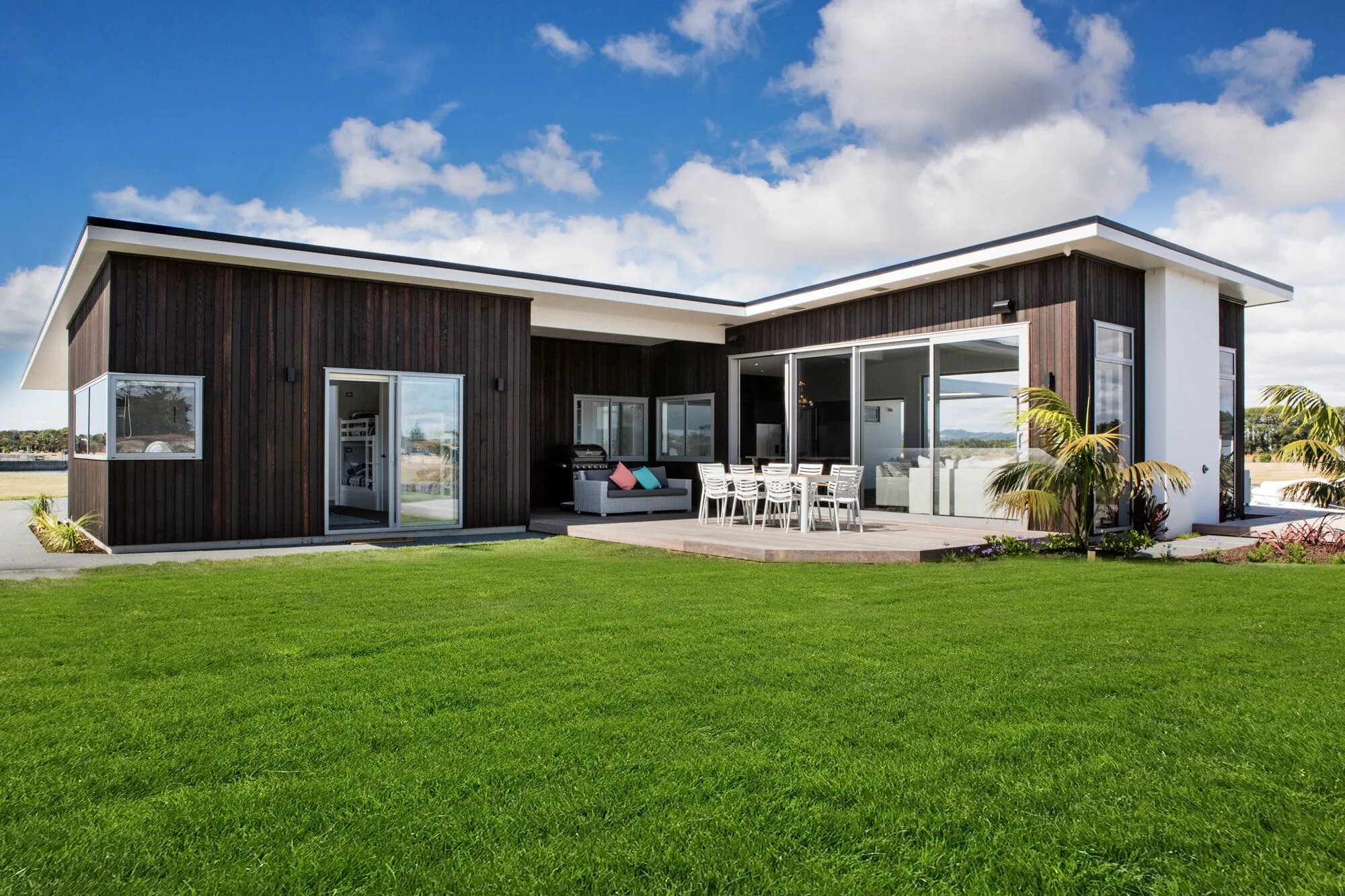 L-shaped dark-clad home with an outdoor living area and lawn