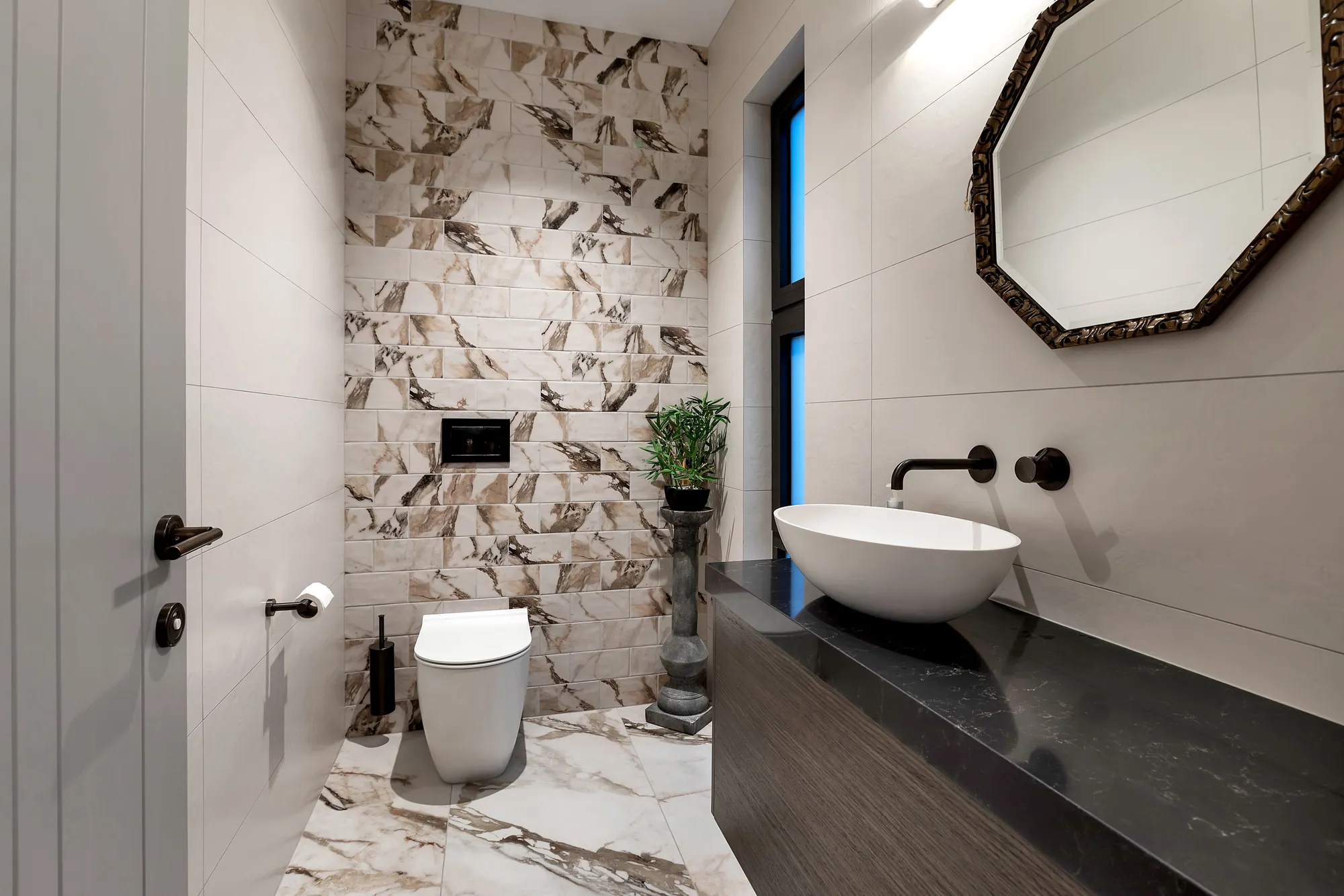 Bathroom with patterned tile, black fittings and a round basin