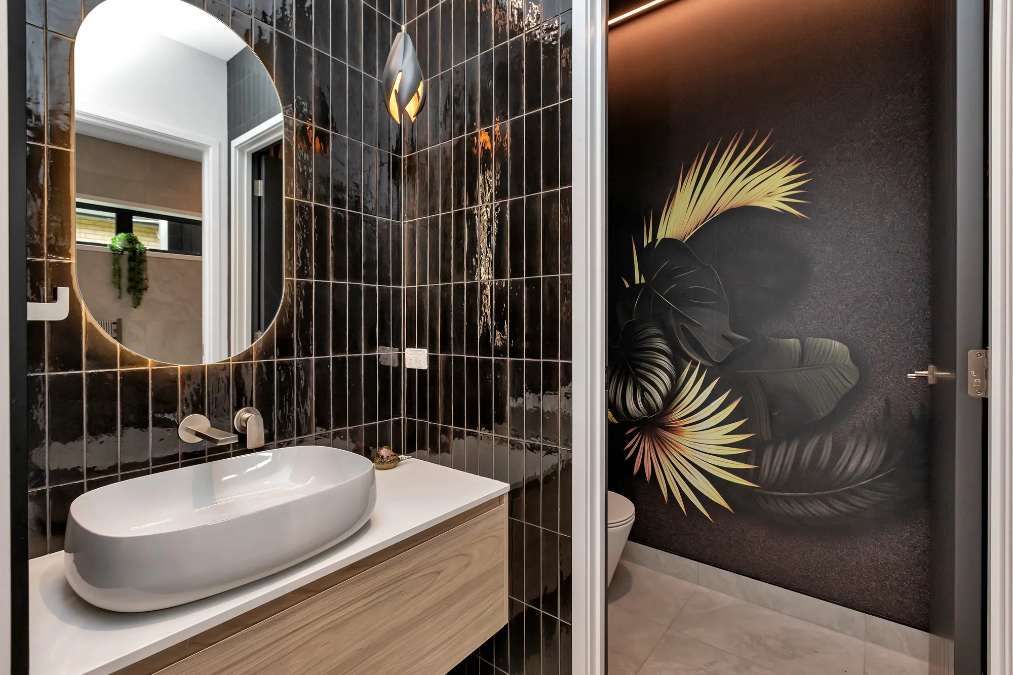 Bathroom in dark tile with a stone basin and back-lit mirror
