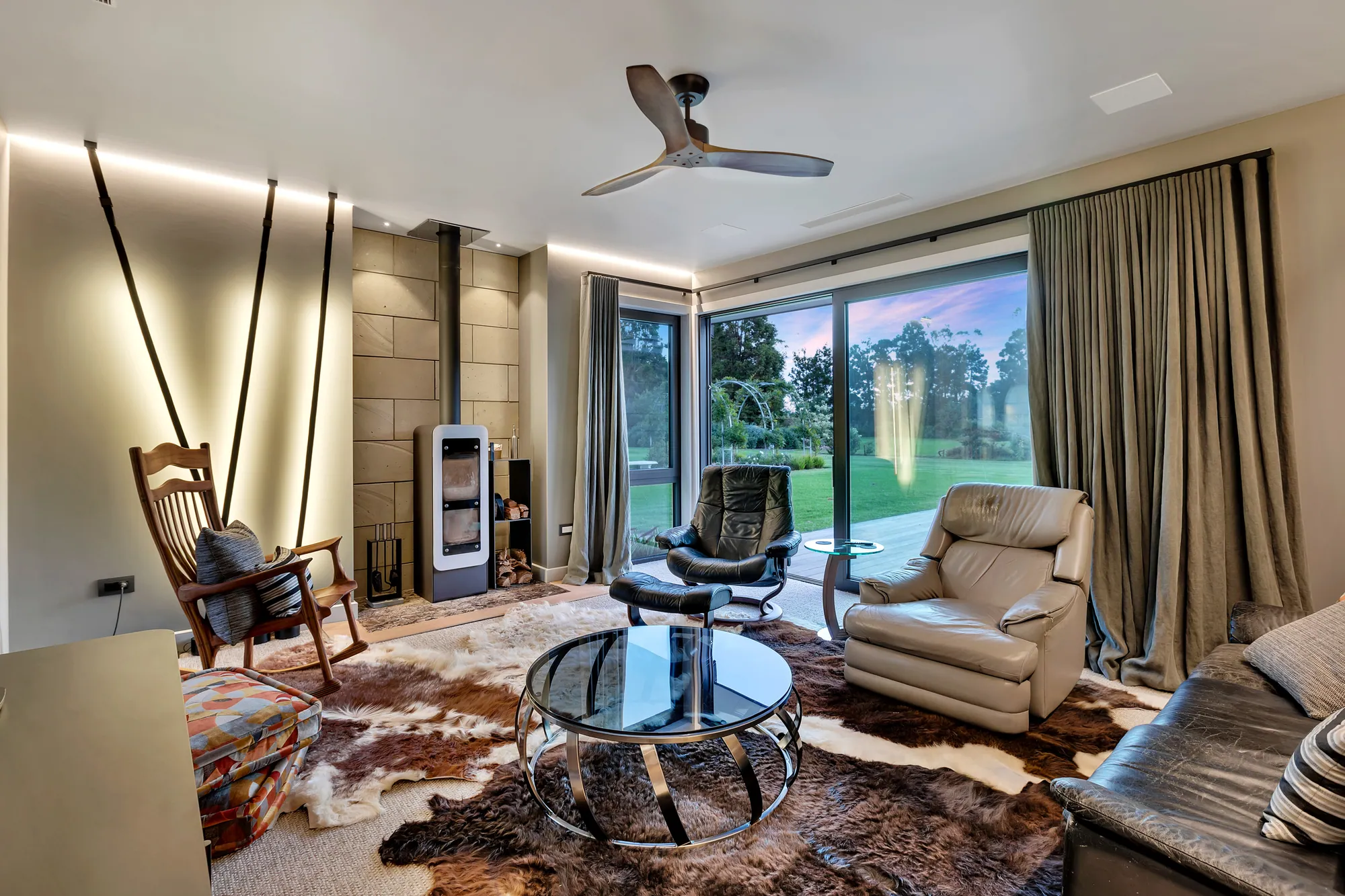 Living room with a wood burner, leather chairs and garden views