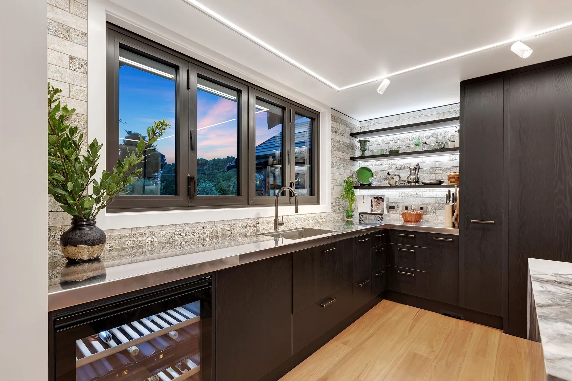Dark kitchen joinery with a stone splashback and wine fridge