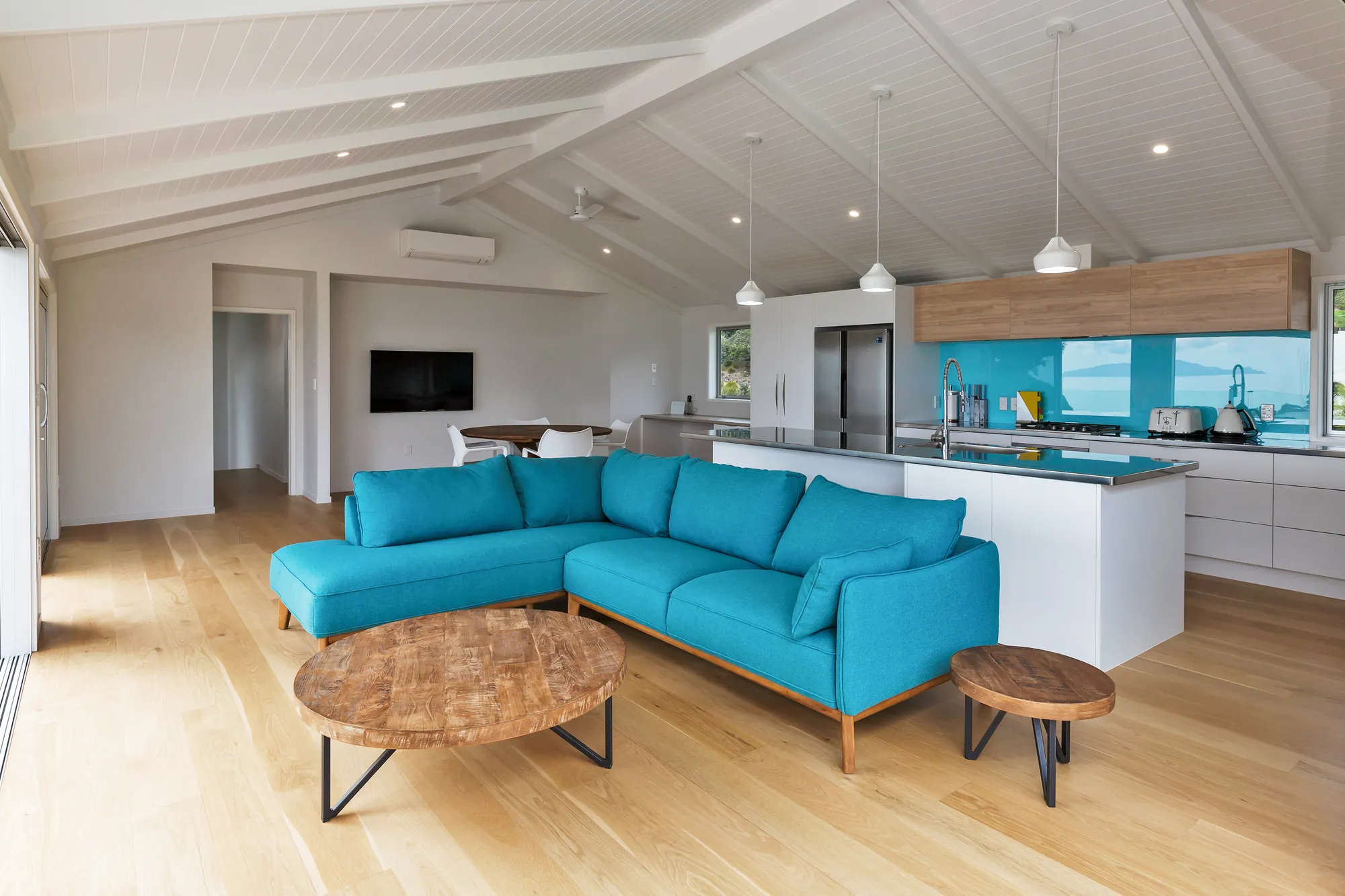 Living room with a turquoise sofa and vaulted timber ceiling