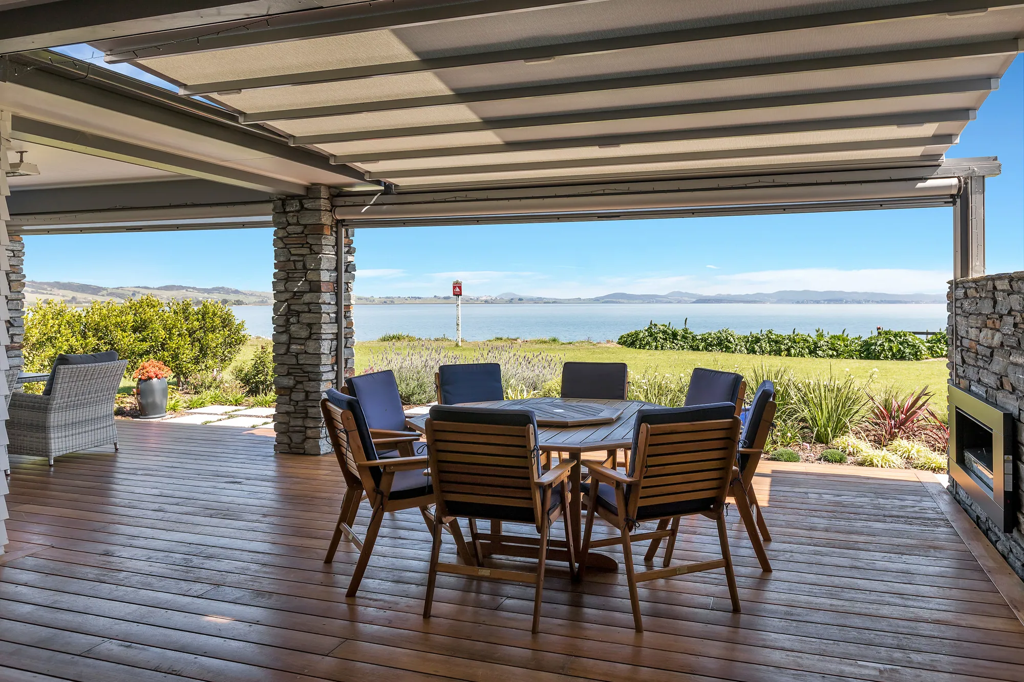 Covered outdoor dining with a stone fireplace, looking out over the harbour
