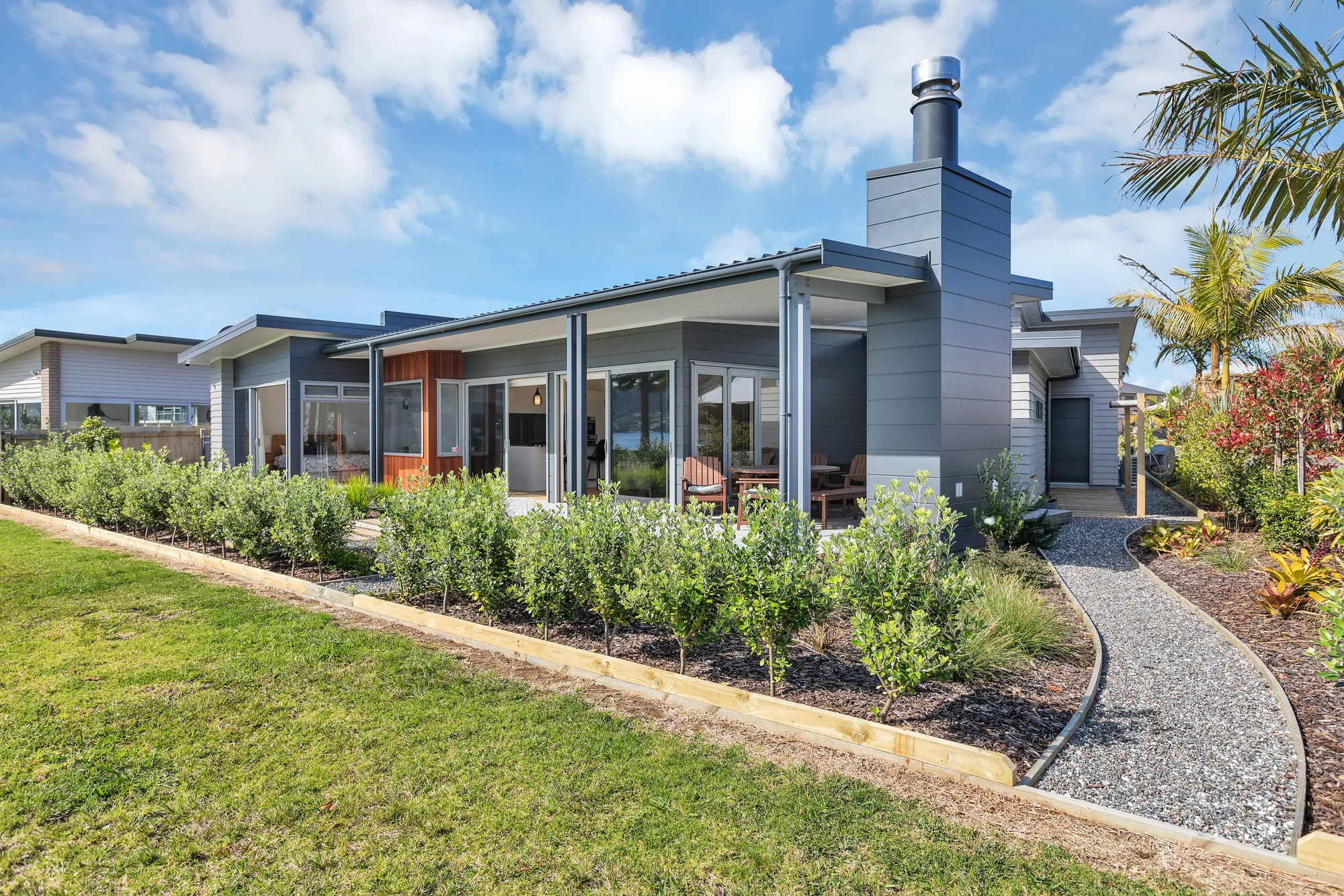 Single-level canal home with a stone chimney and planted approach