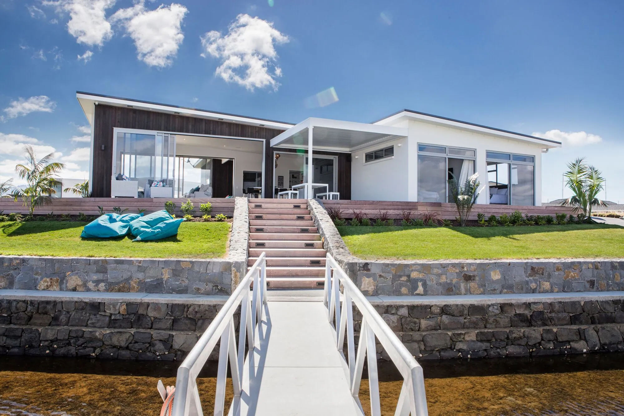Canal home with a stone wall, lawn and gangway to the water