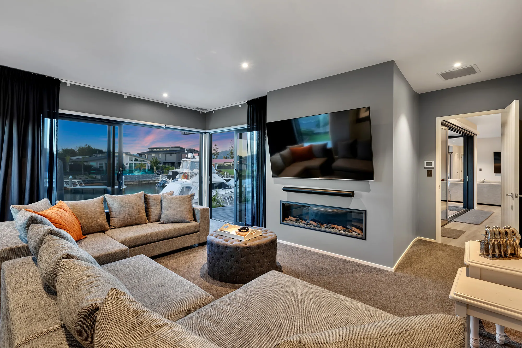 Living room with a fireplace and wide windows to the canal at dusk