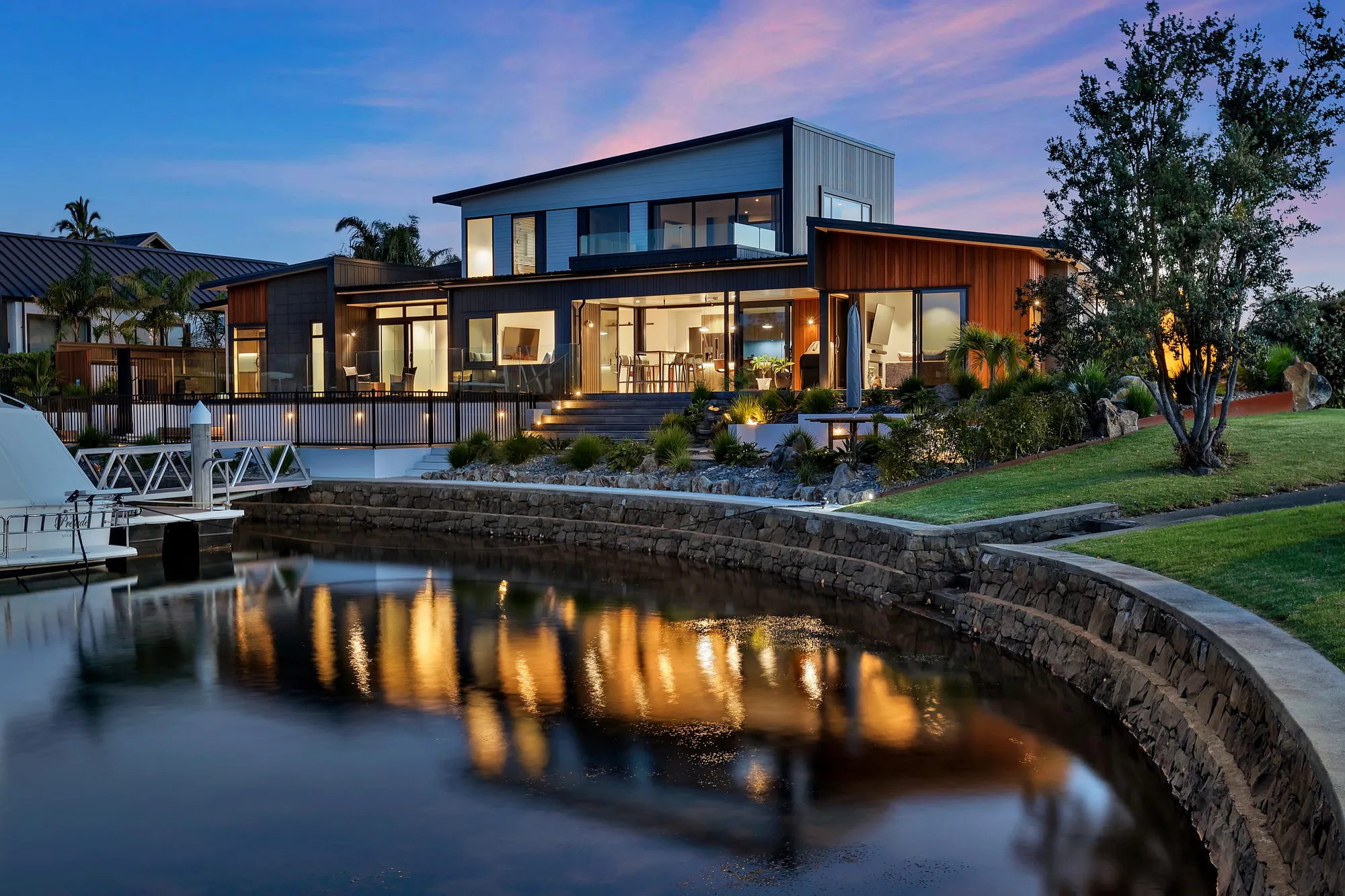 Canal-front home lit at twilight, reflected in still water