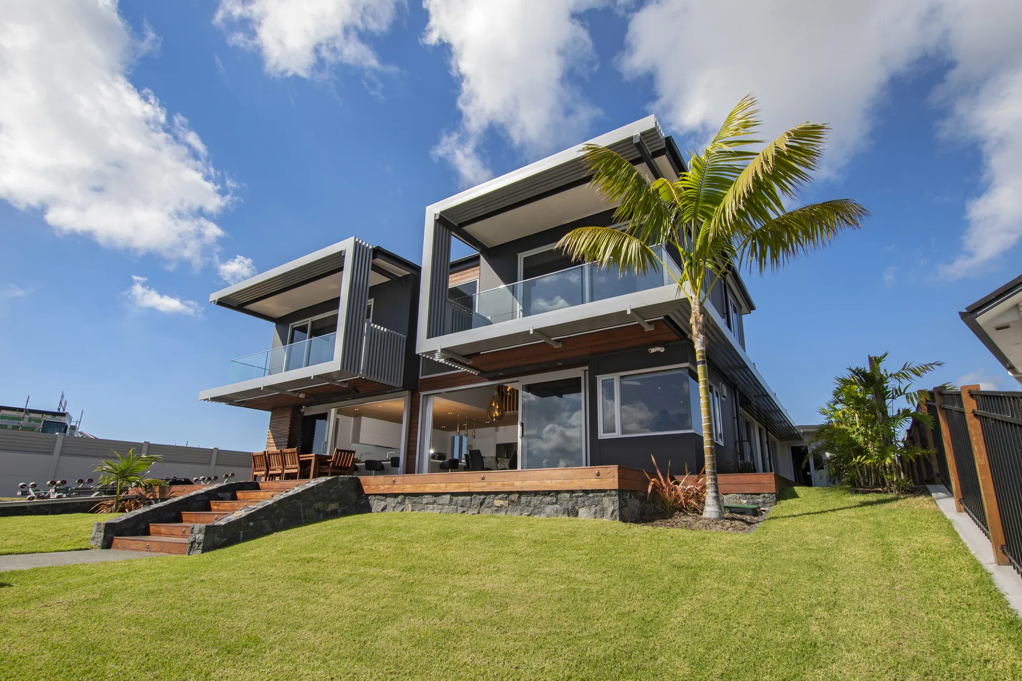 Two-storey Cogan canal home with cantilevered balconies, seen across the lawn