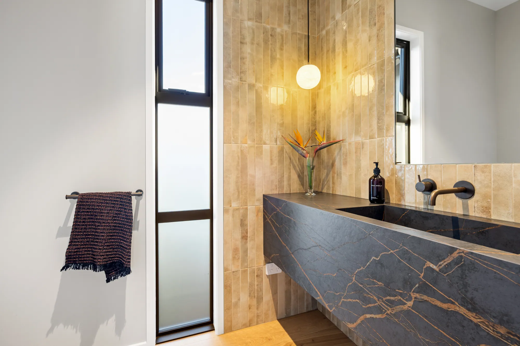 A showhome bathroom with a stone vanity and back-lit mirror